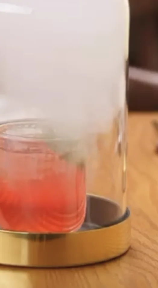 A cocktail being smoked under a glass dome